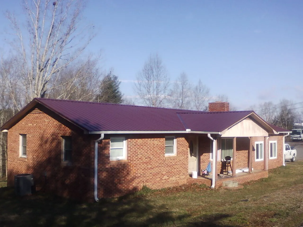 Burgundy metal roof on a brick ranch home with a new addition in Macy