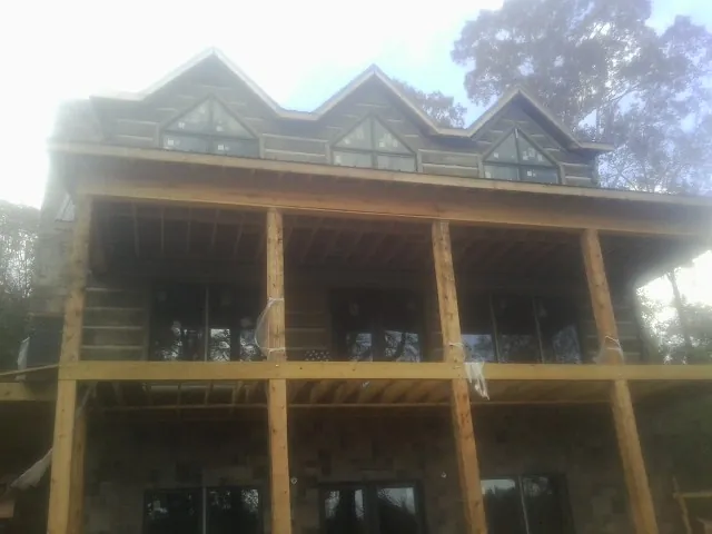Dormers and porch framing on a large log home under construction — Roof Coating work by our crew in Macy