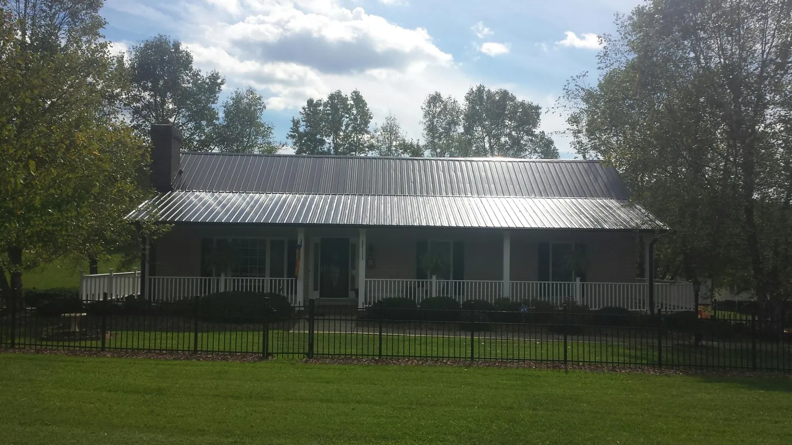 Gray metal roof on a brick ranch with a full width front porch — Gutter Guard Installation work by our crew in Macy