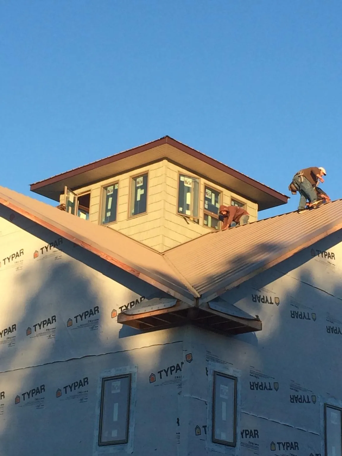 Roofers working around a rooftop cupola on a new metal roof at sunset — Roof Waterproofing in Macy by Roofing Brothers